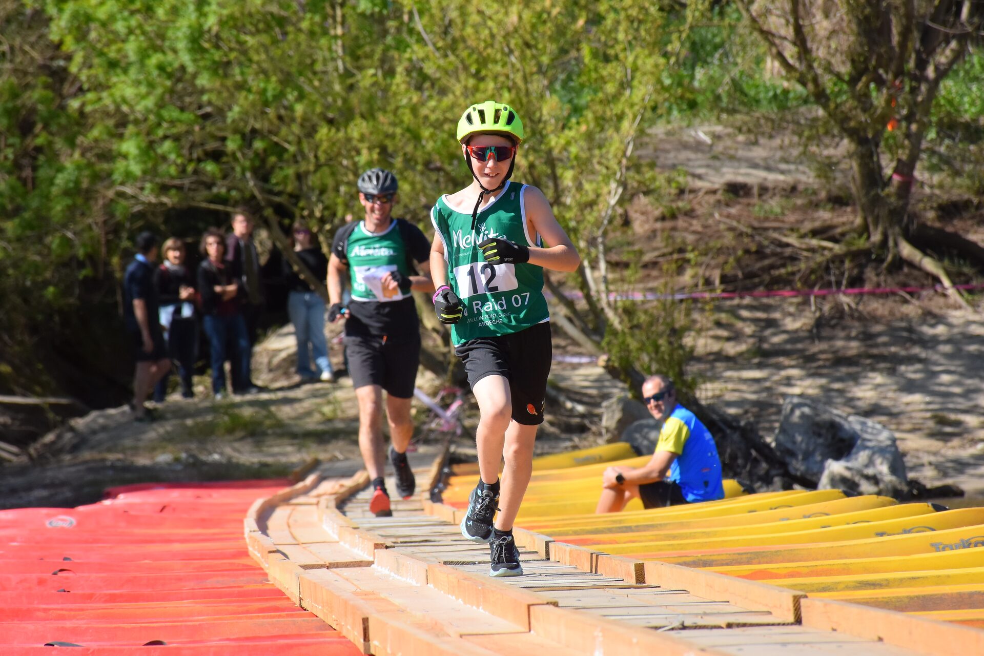 Enfant traversant un pont de bateaux lors d'une course nature en Ardèche