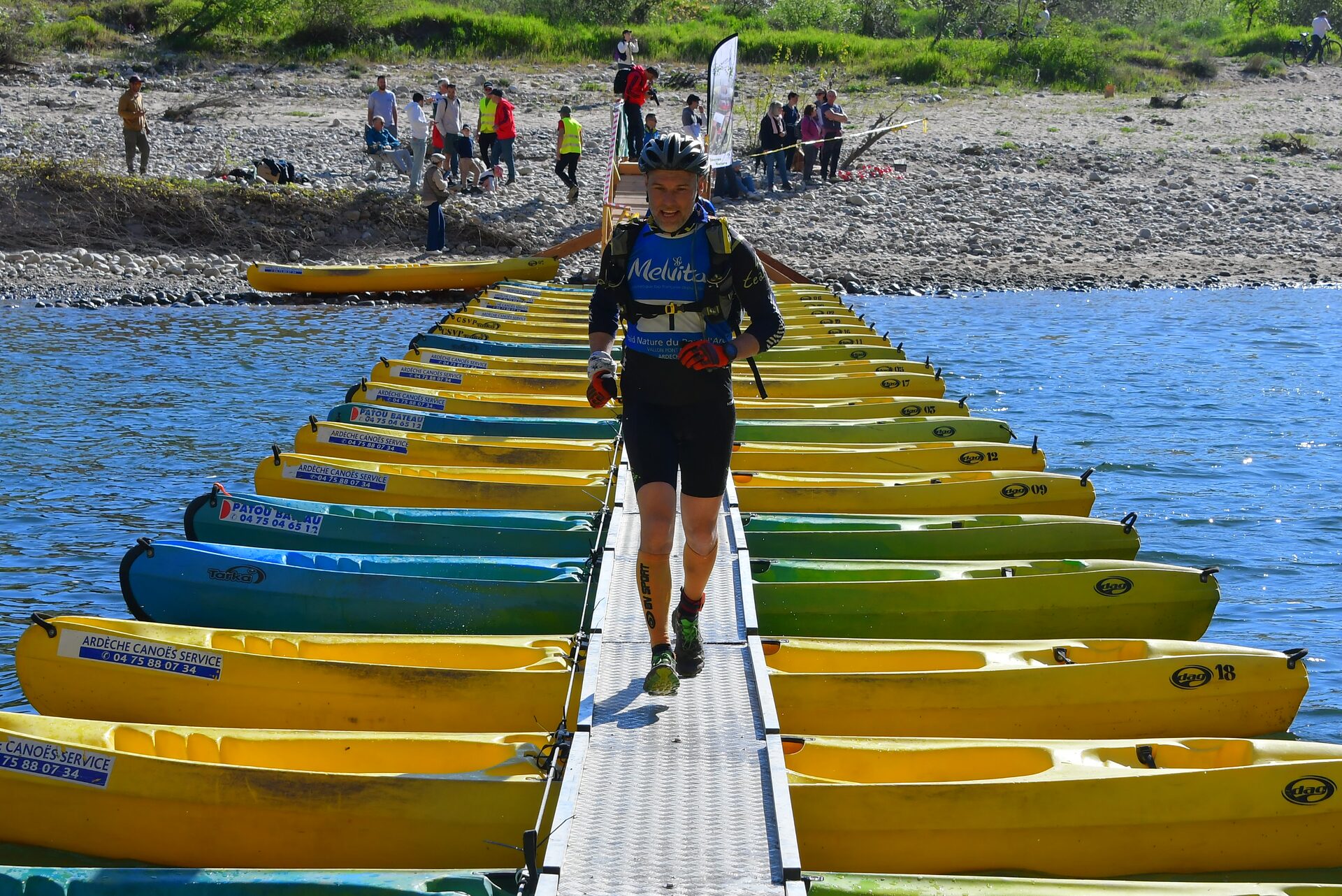 Coureur traversant un pont de bateaux pendant une épreuve de trail en Ardèche à Salavas