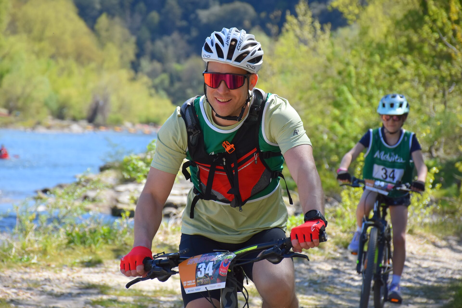 Vététiste au grand sourire avec une jeune coéquipière du Kid Raid lors d'un défi sportif familial en Ardèche